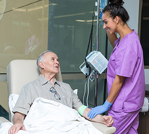 Healthcare provider caring for man having infusion treatment.